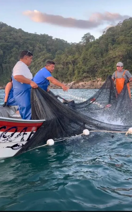 Pescadores recolhendo a rede de um barco
