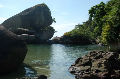 Piscina natural de água calma protegida por grandes pedras de granito